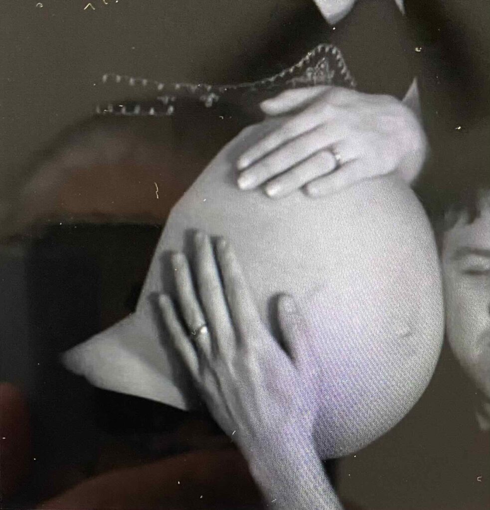 The husband places hi ear on his wife's pregnant  womb to hear and speak to his baby in the uterus.