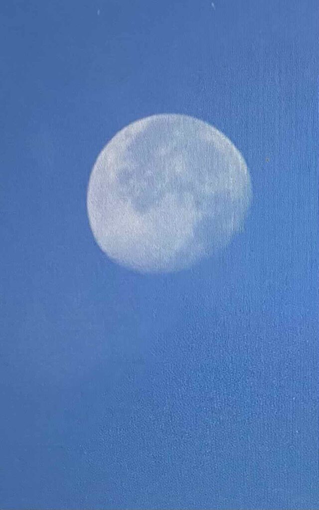 White lunar  moon in blue lit sky.