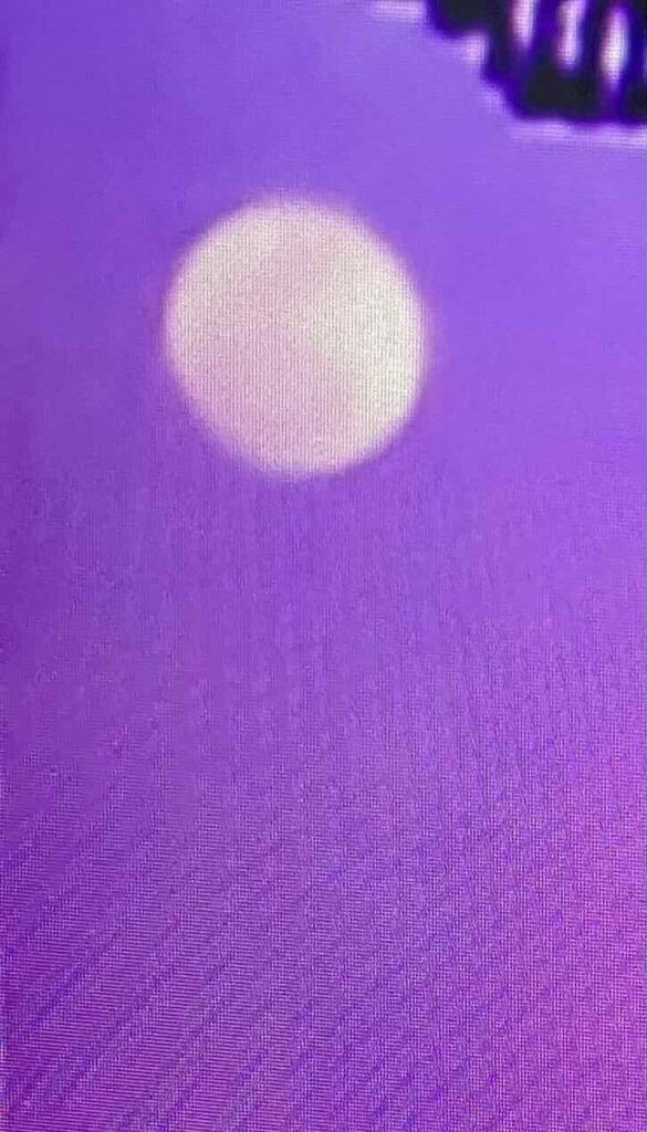 White moon in purple lit sky.